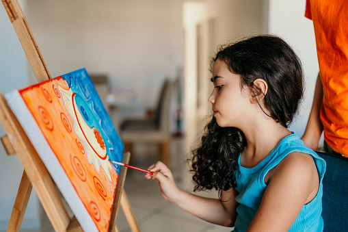 Little girl touching up a painting canvas