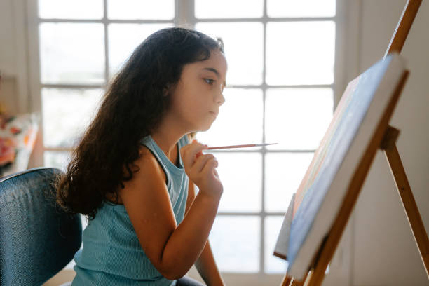 istock Relaxed little girl painting a canvas 1893181321