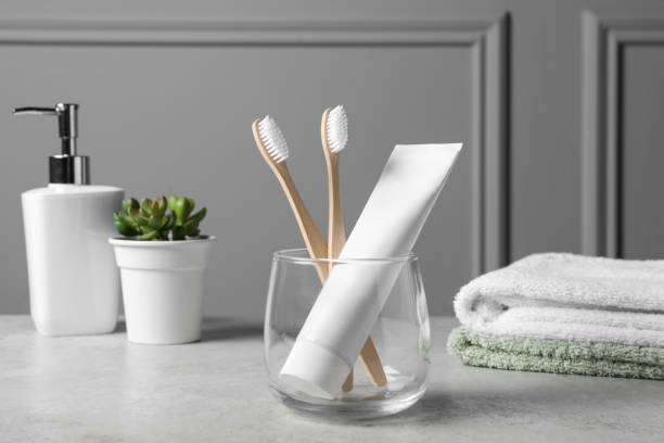 istock Bamboo toothbrushes in holder, toothpaste, houseplant and towels on light grey table 1893230819