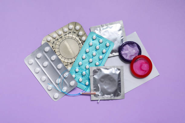 避妊薬、コンドーム、子宮内避妊器具、紫色の背景、平らな寝具。さまざまな避妊方法 - sex object ストックフォトと画像