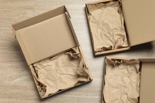 istock Open cardboard boxes with crumpled paper on wooden background, flat lay. Packaging goods 1893245859