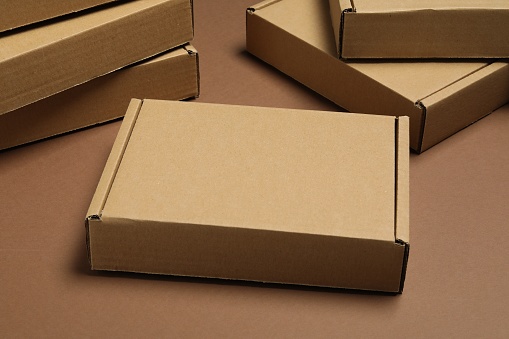 Many closed cardboard boxes on brown background, closeup