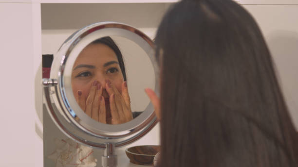 istock CLOSE UP Young lady self massaging her pretty face in cosmetic mirror reflection 1893262571