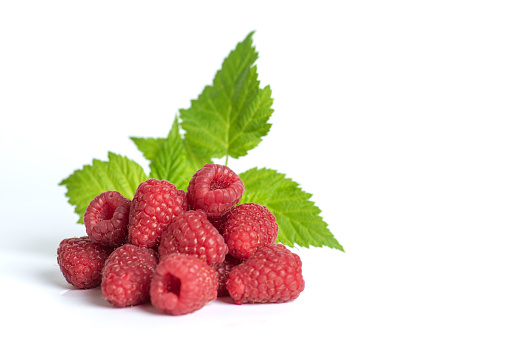 Bunch of red ripe raspberries with leaves isolated on white background. With copy space