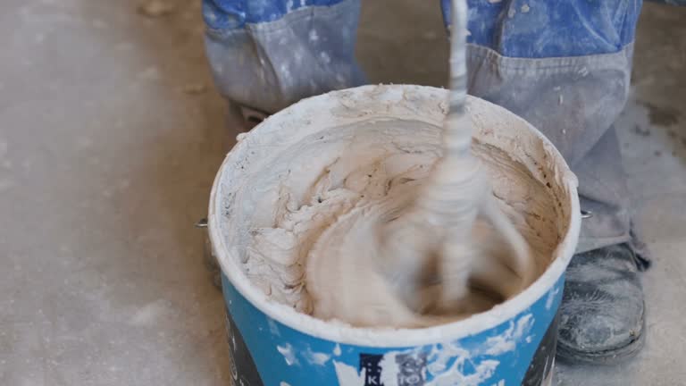 Mixing plaster solution in a bucket, using an electric drill