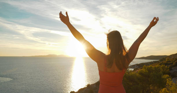 istock LENS FLARE, CLOSE UP: Attractive lady embraces gorgeous golden sunrise on Hvar 1893304552