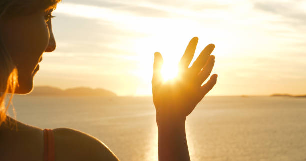 istock CLOSE UP, LENS FLARE: Female hand waves at golden setting sun over Adriatic Sea 1893304553