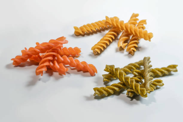 Various legume pasta fusilli made from chickpeas, mung beans and red lentils, alternative noodles for a healthy diet, light gray background, close-up shot, copy space, selected focus