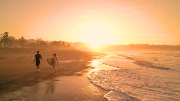 istock AERIAL: Chatty friends coming back in golden light after riding waves in Pacific 1893318460