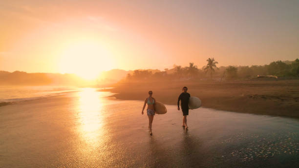 istock AERIAL: Beautiful sun reflection on sandy foreshore and surfers in golden light 1893318979