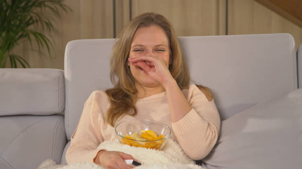 istock CLOSE UP: Smiling woman sitting on comfortable sofa and watching TV comedy 1893347534
