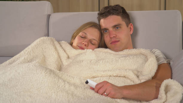 istock CLOSE UP: Handsome guy watching TV while his lady is napping on his shoulder 1893353686