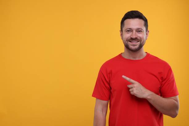 istock Special promotion. Smiling man pointing at something on orange background. Space for text 1893378678