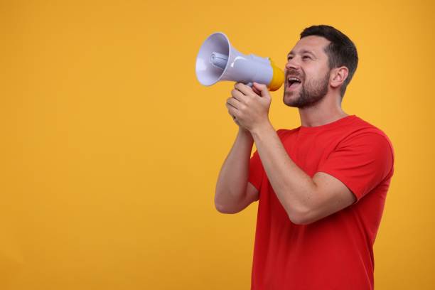 istock Special promotion. Man shouting in megaphone on orange background. Space for text 1893379189