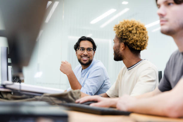 istock Diverse male college friends chat during computer lab 1893496061