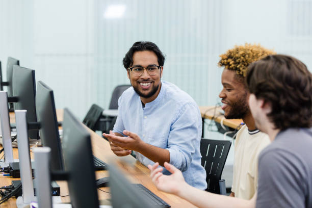istock Male teacher's assistant helps male students with computer project 1893496062