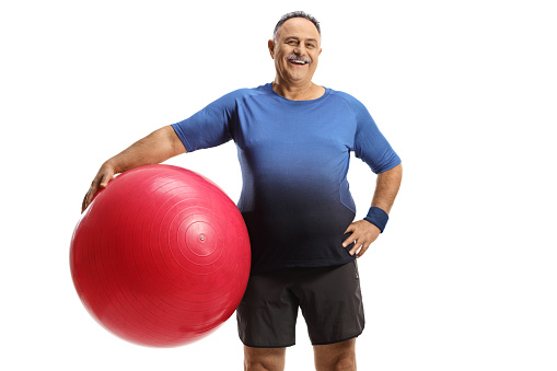 Mature man with a fitness exercise ball isolated on white background