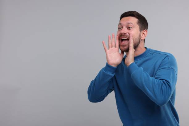 istock Special promotion. Man shouting to announce information on light grey background. Space for text 1893532619