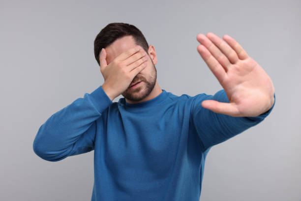 istock Embarrassed man covering face on light grey background 1893532622