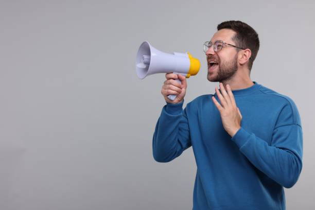 istock Special promotion. Man shouting in megaphone on light grey background. Space for text 1893532634