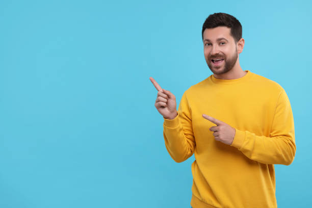 istock Special promotion. Handsome man pointing at something on light blue background. Space for text 1893533148