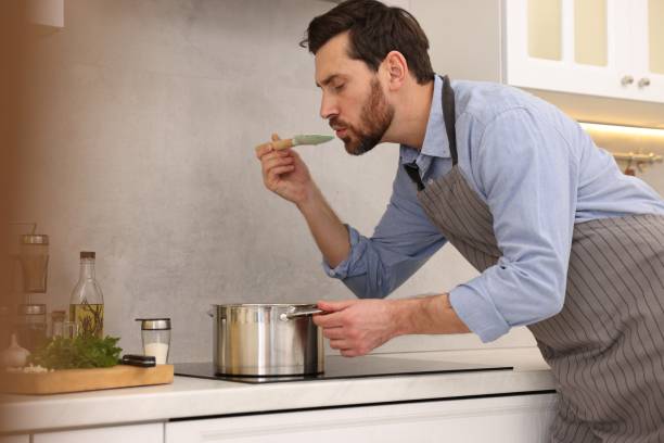 istock Man tasting delicious soup with spoon in kitchen 1893538221
