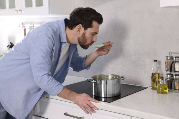 istock Man tasting delicious soup with spoon in kitchen 1893538748
