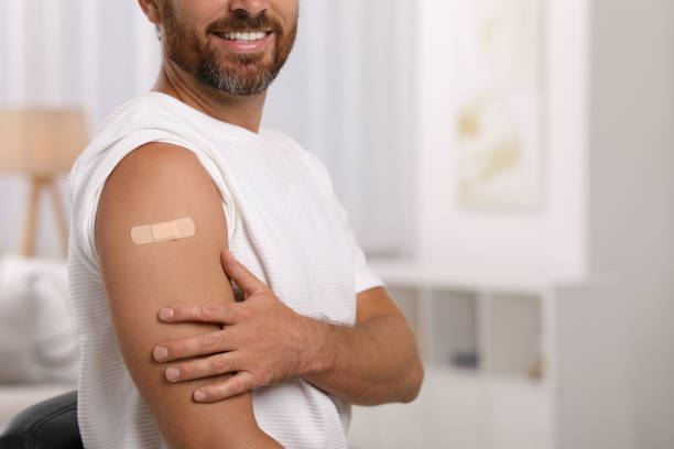 istock Man with sticking plaster on arm after vaccination at home, closeup. Space for text 1893573827