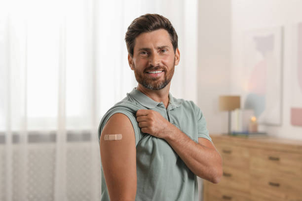 istock Man with sticking plaster on arm after vaccination at home 1893576418