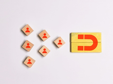 Magnet icon pulling figure icons on the wooden cubes. Customer attraction and retention concept.