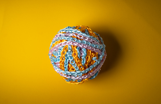 Colorful ball of wool on yellow background