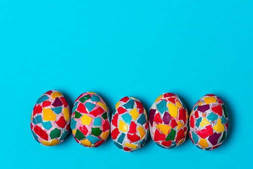 Colorful pattern of abstract decorated Easter eggs on paper blue background. With copy space