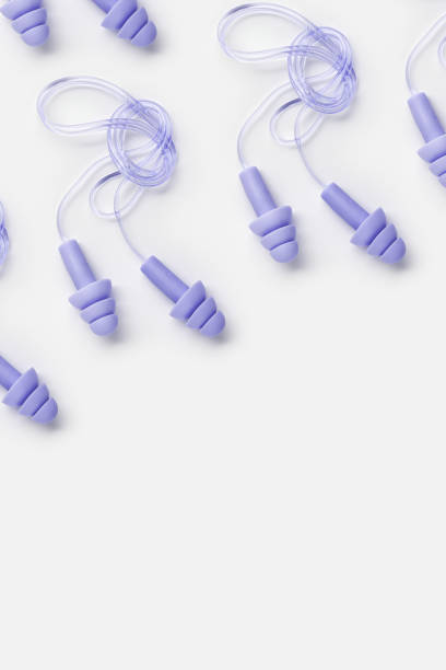 istock Reusable silicone violet color earplugs, for swim, sleep, rest as minimal trend pattern on white background. Soft, flexible ear plug on cord against noise, protect hear, top view, flat lay 1893720046