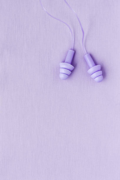 istock Reusable silicone earplugs purple color on colored textile background, copy space. Against noise and water Ear plug on string, for swim, sleep, protect hear, aesthetic top view, minimal style 1893720058