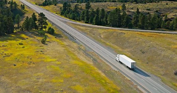 Aerial view of a truck driving across rural scenery outside of Billings in Stillwater County, Montana, near the small town of Park City, on a clear day in Fall.