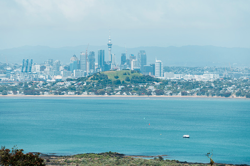 Rangitoto Island is a young volcanic island on the outskirts of Auckland and a popular day hiking destination from Auckland. The image depicts the view from Rangitoto Island towards Auckland, with the Auckland city skyline unfolding before your eyes.