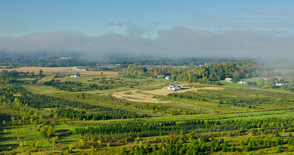 Aerial view of houses surrounded by farmland in Hughesville, a borough in Lycoming County, Pennsylvania on a misty morning in Fall.