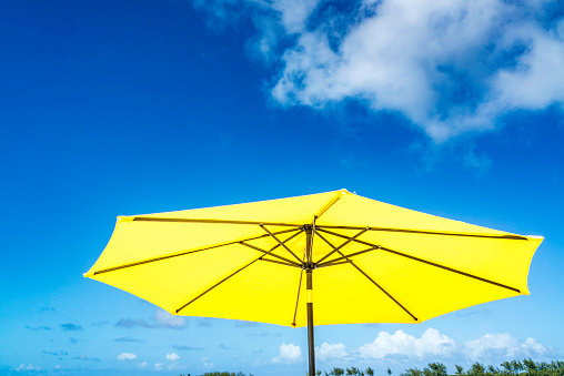 Blue sandal flip flop and towel on yellow sand. Summer fun time and accessories on the beach, summer vacations, copy space.