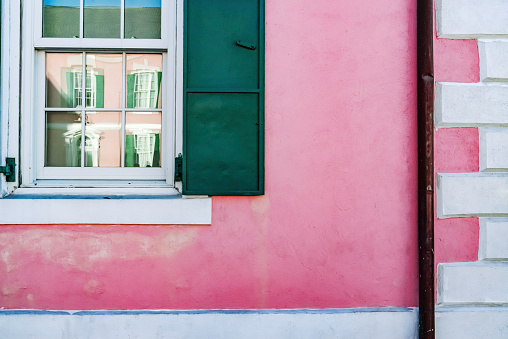 Beautiful colorful house facade on Burano island, north Italy. Red two windows with wooden shutters