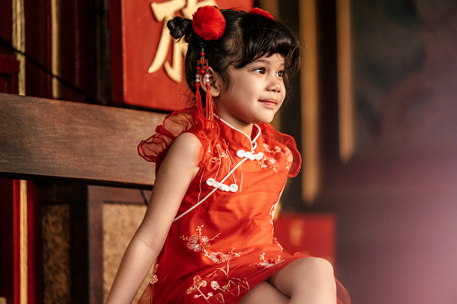 A little girl in traditional Chinese clothing makes a wish to celebrate the Chinese new year at Chinese temple