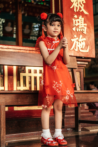 A little girl in traditional Chinese clothing makes a wish to celebrate the Chinese new year at Chinese temple