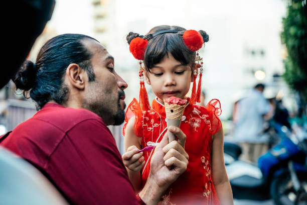 Lovely little girl with father in traditional Chinese clothing having ice cream cone Lovely little girl with father in traditional Chinese clothing having ice cream cone joyfully on street asian little chinese girls eating ice cream stock pictures, royalty-free photos & images