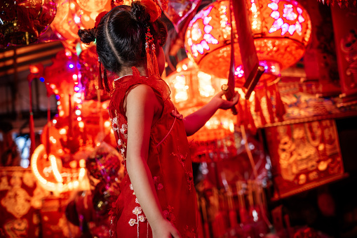 Lovely little girl hand red Chinese lanterns to celebrate the new year on city street