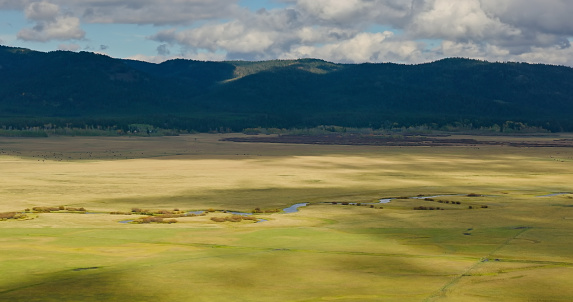 Aerial view of Henry's Fork on farmland near West Yellowstone, a town in southern Montana, on an overcast day in Fall. The town of West Yellowstone is adjacent to Yellowstone National Park.