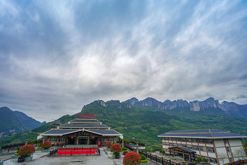 Visitor center with majestic mountains and dramatic sky in the background. Enshi Grand Canyon Qixingzhai Scenic Area, Enshi City, Hubei, China.