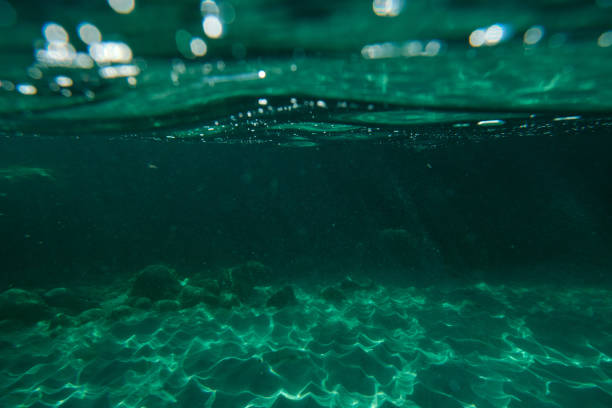 Underwater view of abstract background of clear blue water of sea with stones of different sizes at bottom