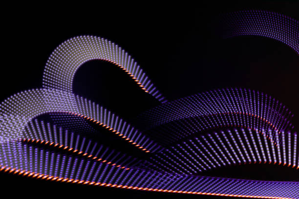 istock Violet and red neon curved wave of light as curls with dotted stripes on black background, pattern. Abstract background with motion light effect, light painting in holiday style. 1894183887