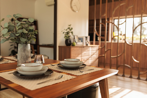 Dinning table arranged with plates and cutlery in a modern house.