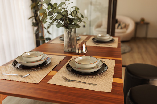Photo of a dining table with colorful place mats, plates and utensils.