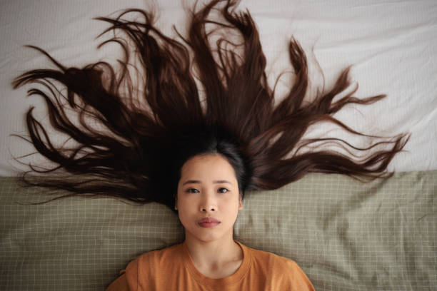 Portrait of a young woman lying on the bed, looking seriously at the camera.